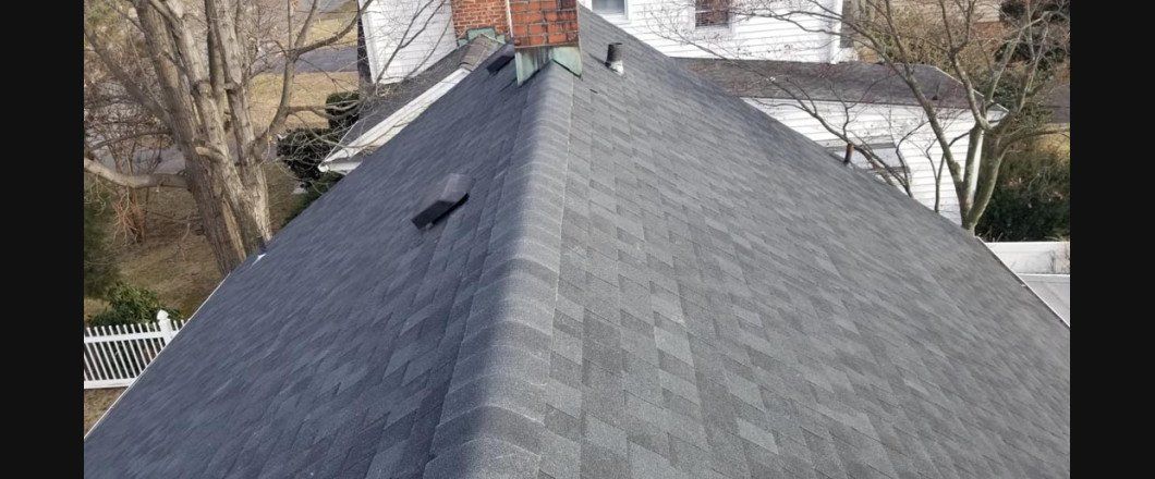 An aerial view of a roof with a chimney and trees in the background.
