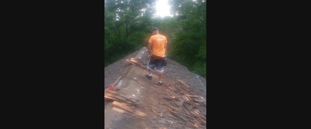 A man in an orange shirt is standing on a train track.