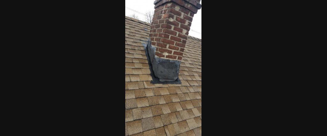A brick chimney is sitting on top of a wooden roof.