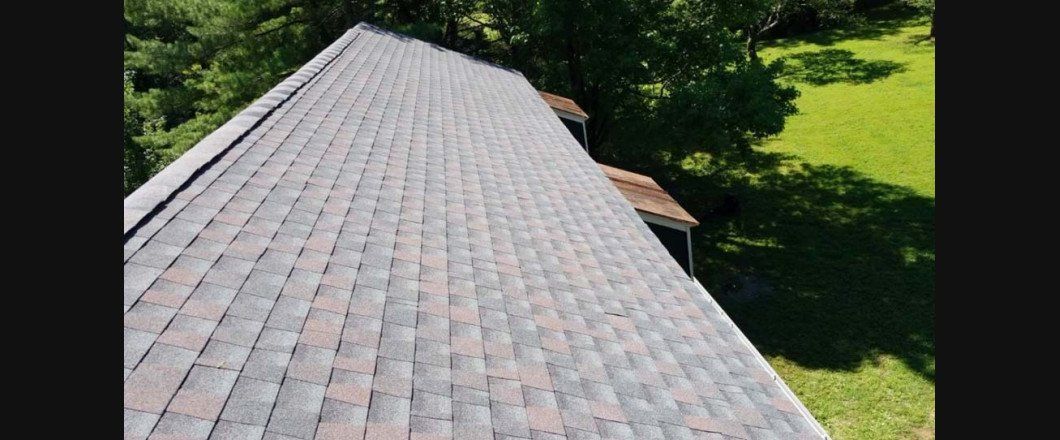 An aerial view of a roof with a lot of shingles and trees in the background.