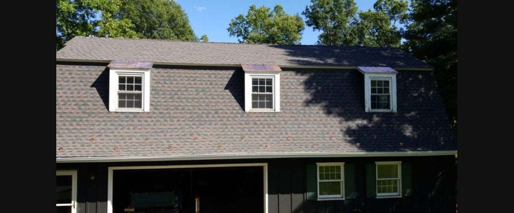 A black house with a gray roof and white windows