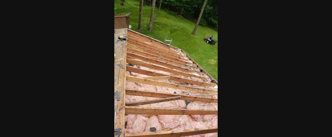 A person is standing on top of a wooden roof.