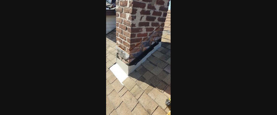 A brick chimney is sitting on a brick sidewalk next to a brick wall.