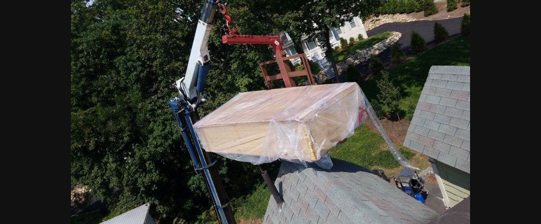 A crane is lifting a box on top of a roof.