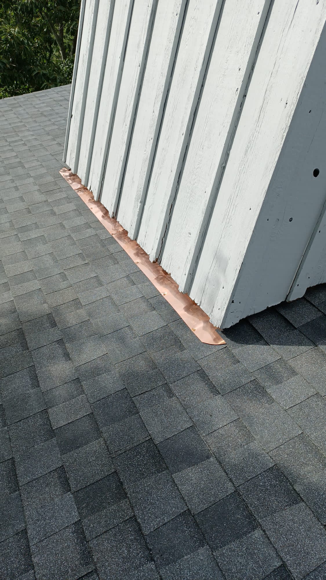 A close up of a roof with a white building in the background.