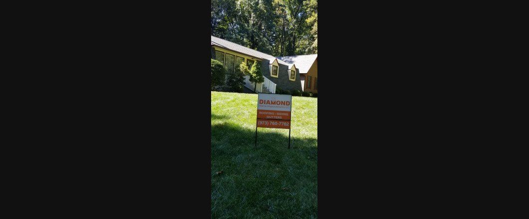 A for sale sign is sitting in the grass in front of a house.