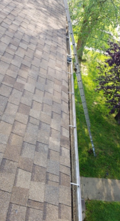 A gutter on the roof of a house with a ladder attached to it.