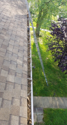 A gutter on the roof of a house with a ladder attached to it.