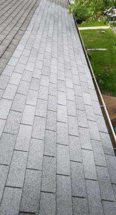 A close up of a roof with shingles and a gutter.