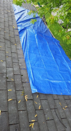 A blue tarp is laying on top of a roof
