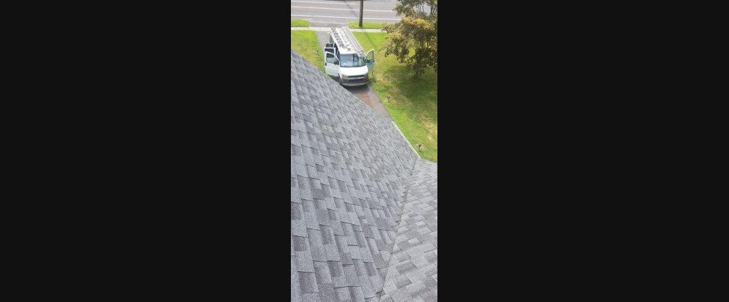 A white van is driving down a road next to a roof.