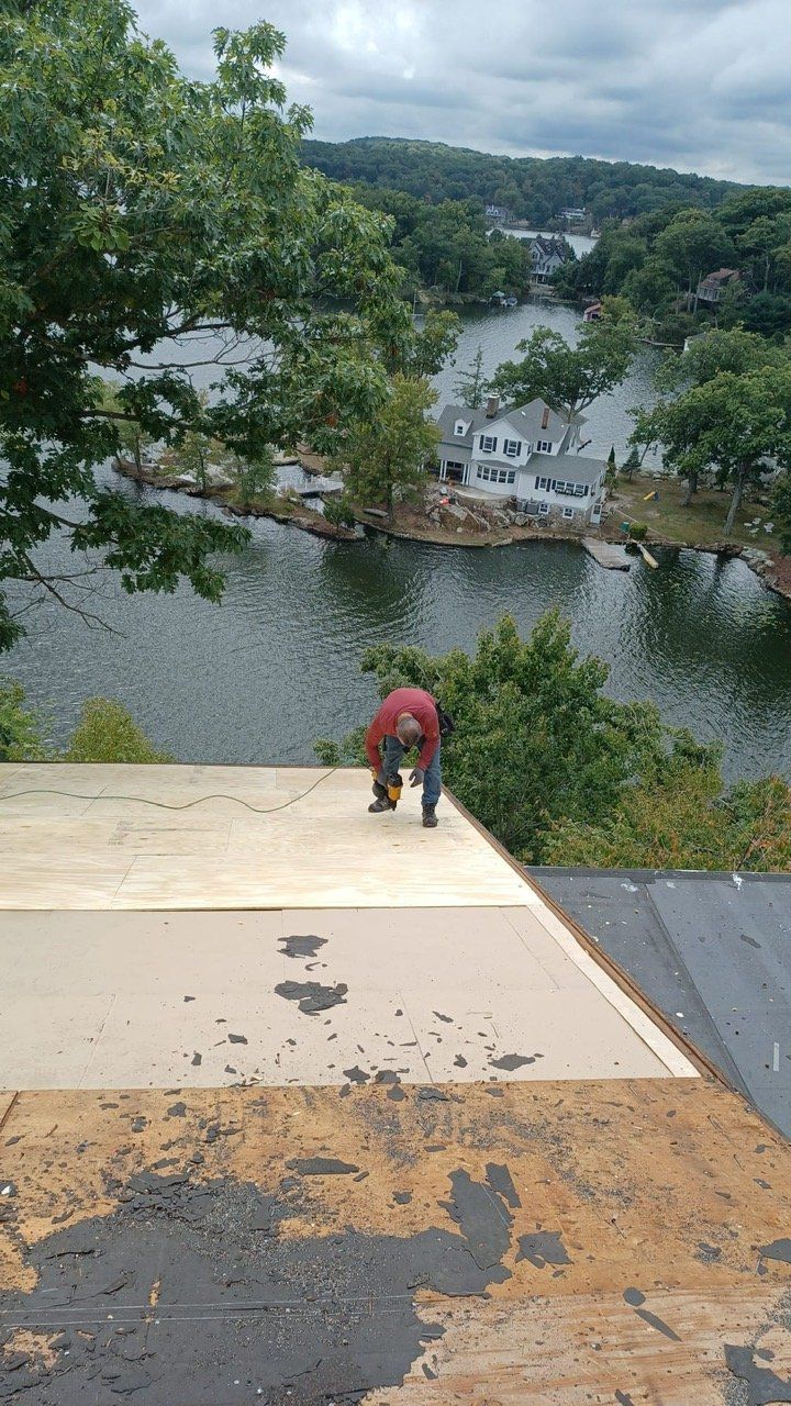 A man is working on a roof overlooking a lake.