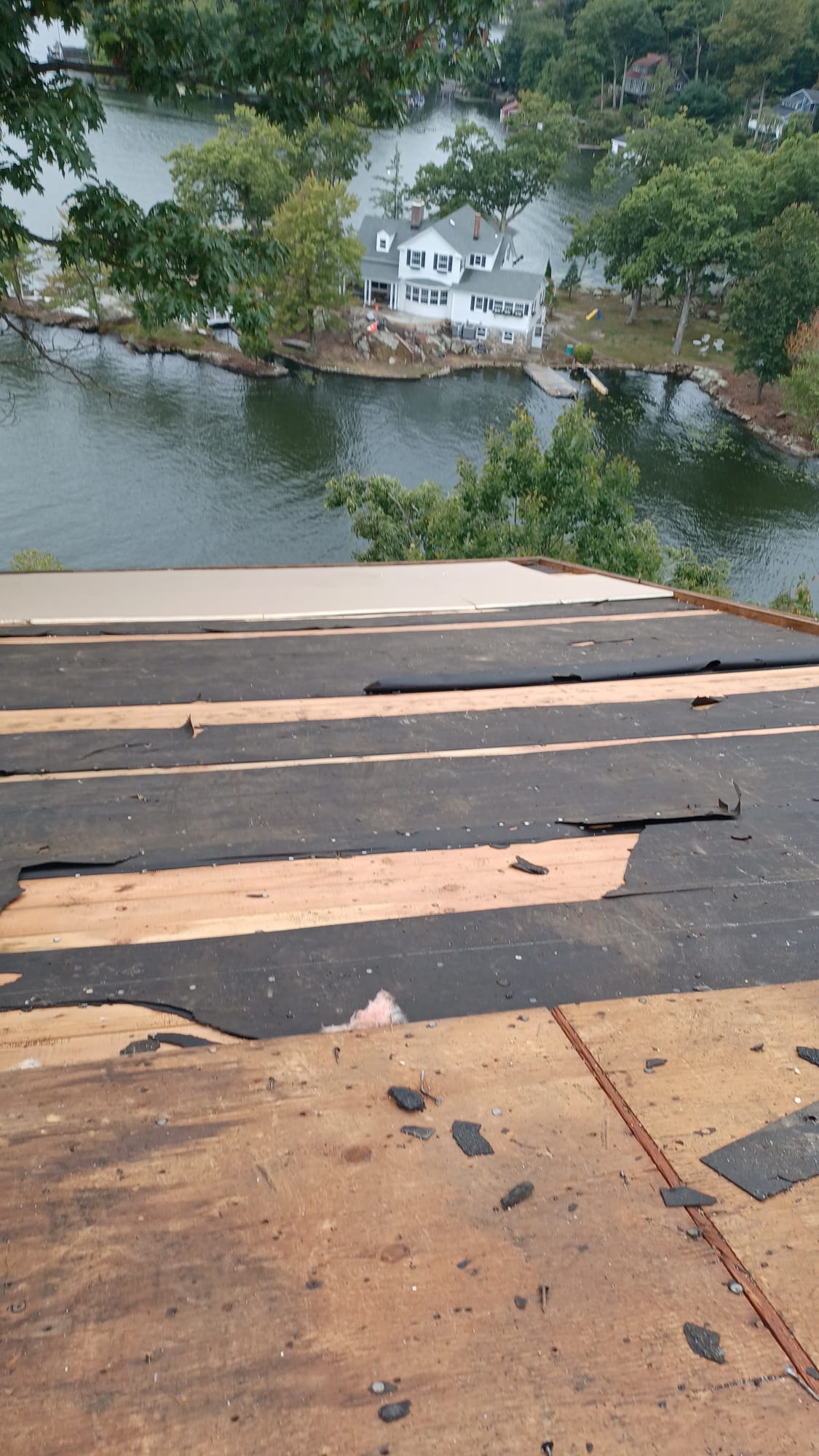 A roof with a view of a lake and a house in the background.