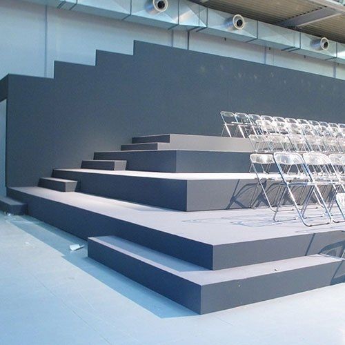 Gray stage with steps, rows of clear chairs.