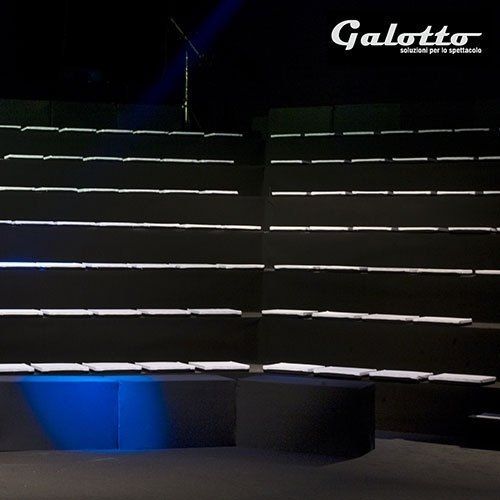 Black display shelves with integrated white lighting in a dark room. A blue light illuminates the floor.