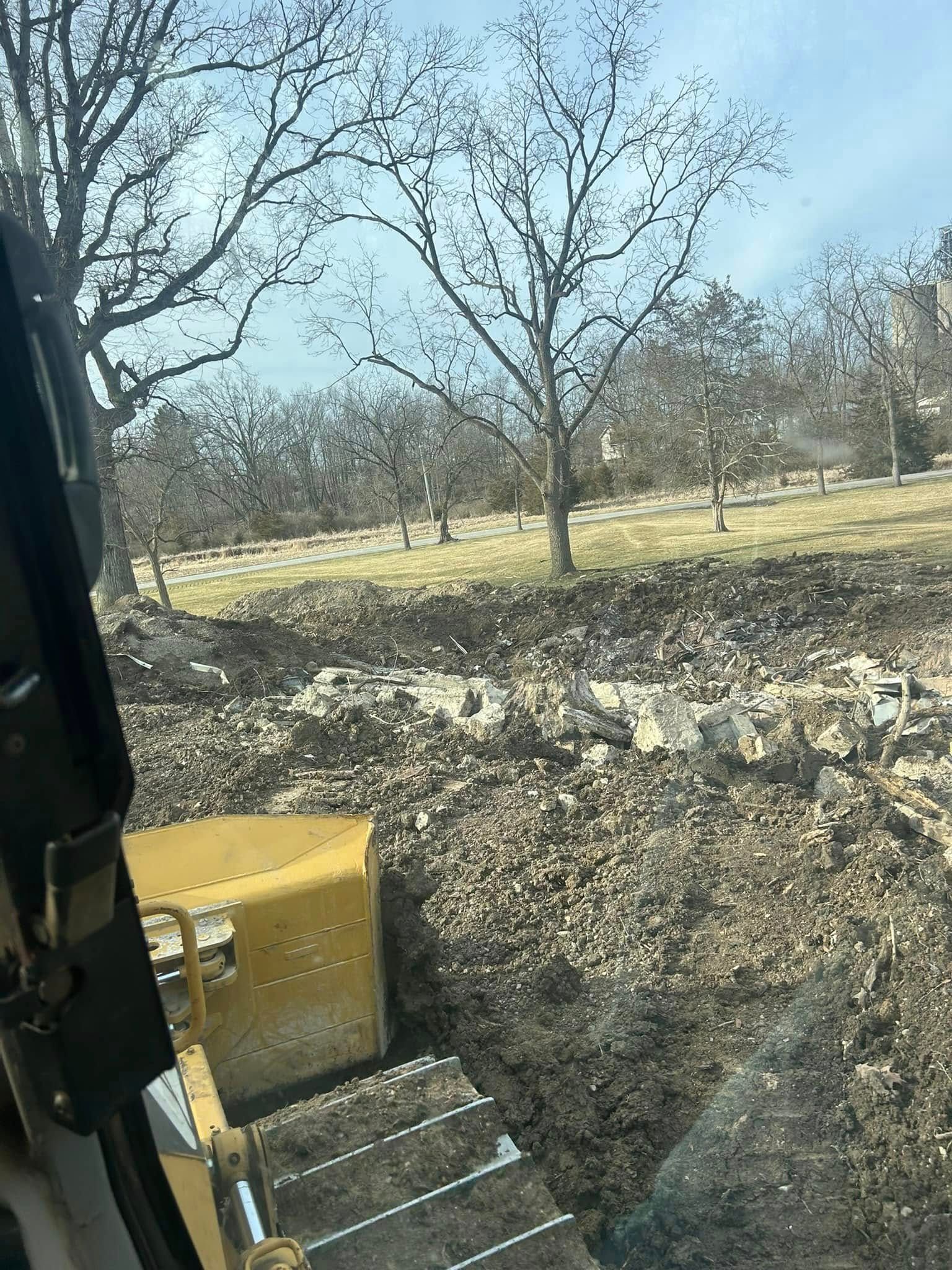 Yellow bulldozer clearing land with trees in the background.