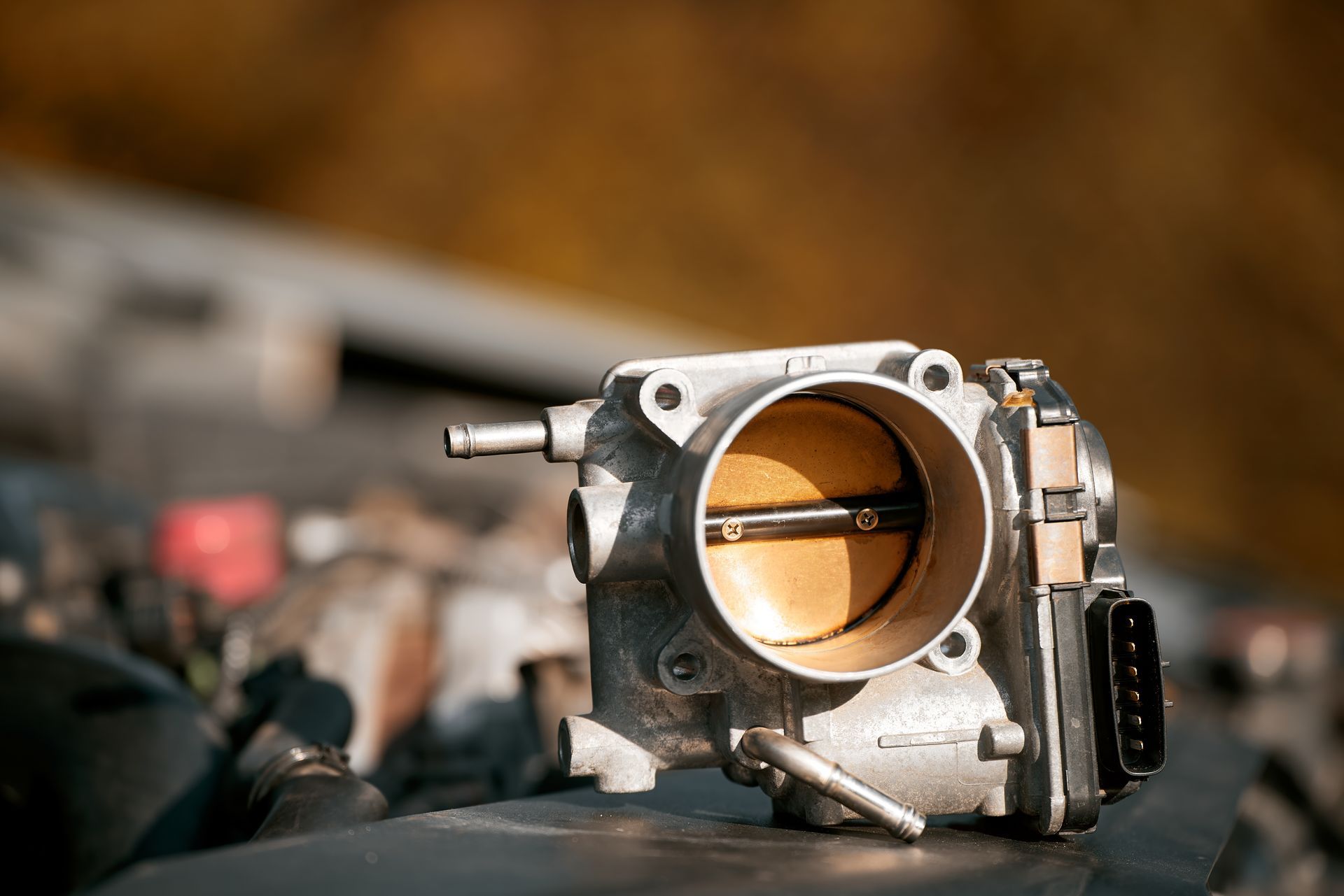 Throttle body of a car engine, close up, on car hood.