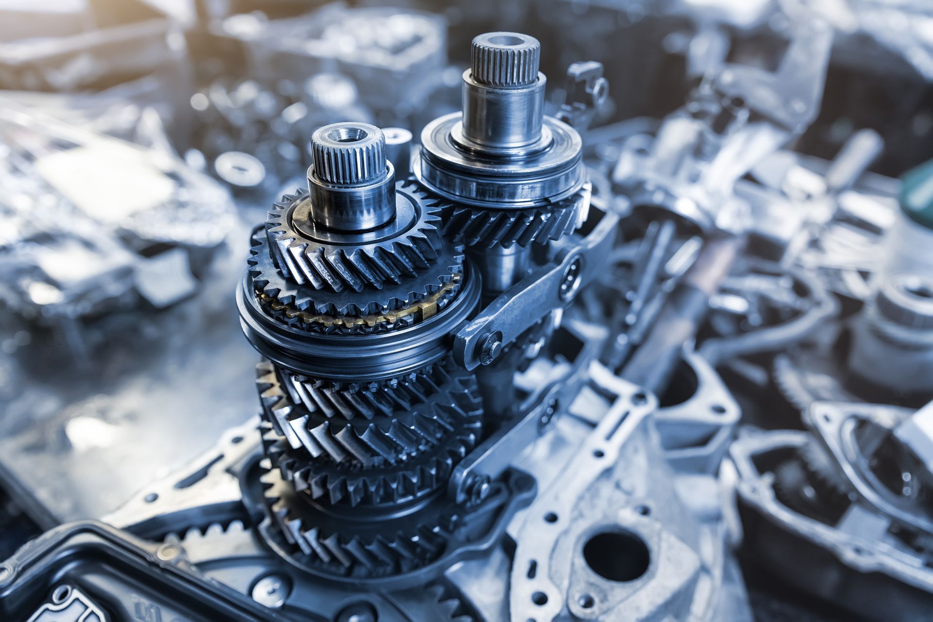 Gears from a vehicle's transmission, metallic blue tones, close up, workshop setting.