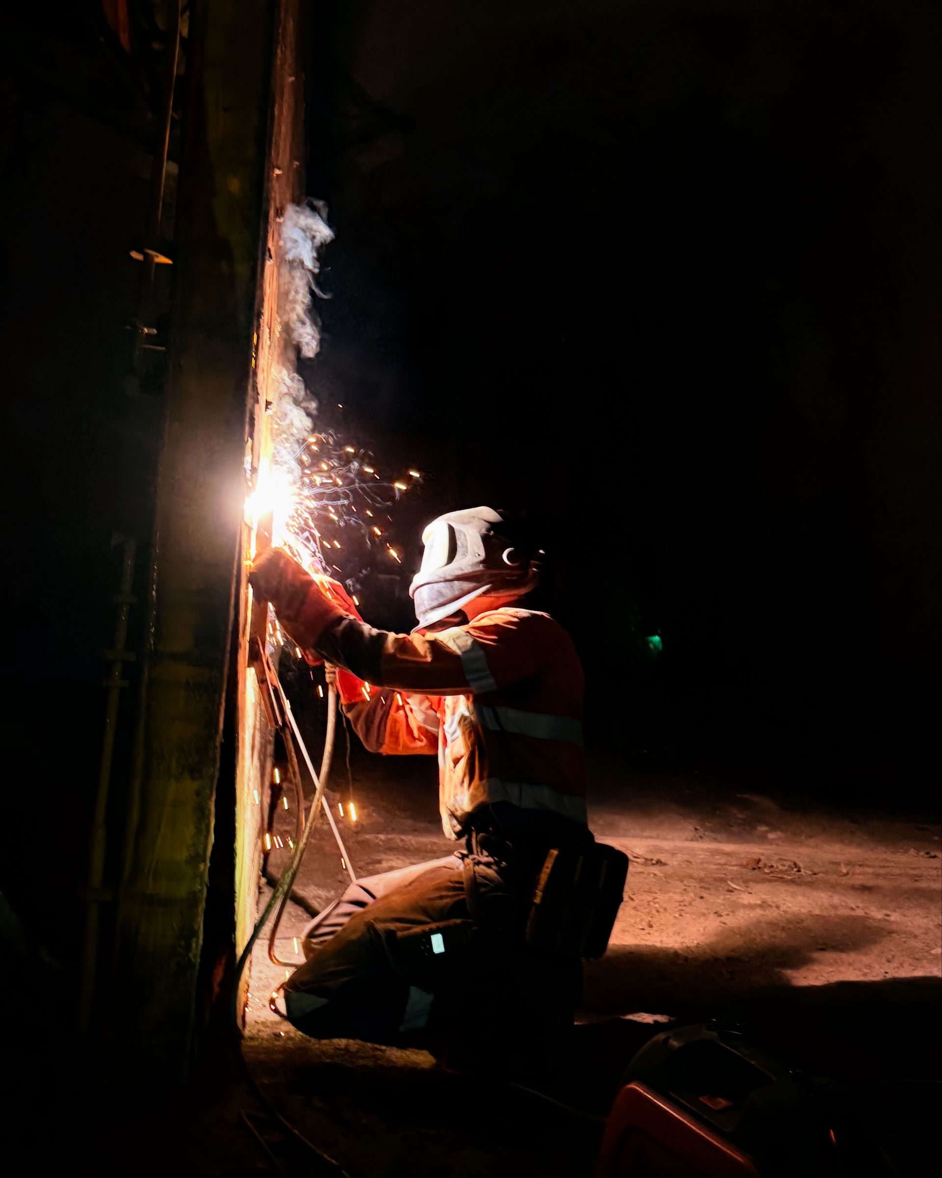 Welder Wearing Protective Gear Kneels — Lincoln Fabrication in Miles End, QLD