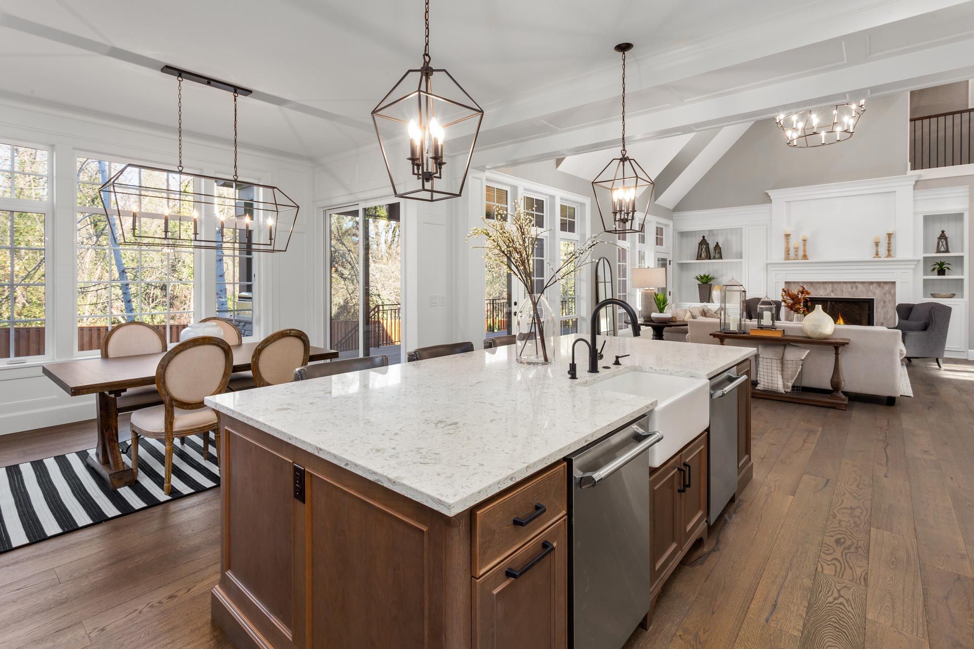 Bright open-plan kitchen and dining room with large island, white cabinets, and gray seating area