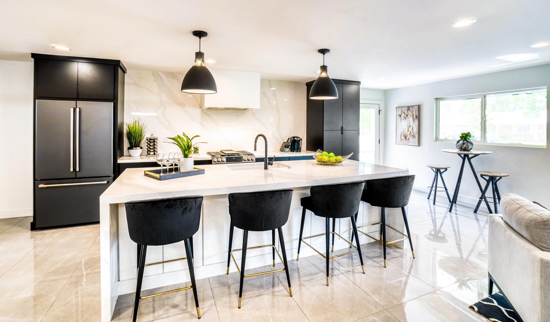 Modern kitchen with black island, pendant lights, stools, and bright white cabinets