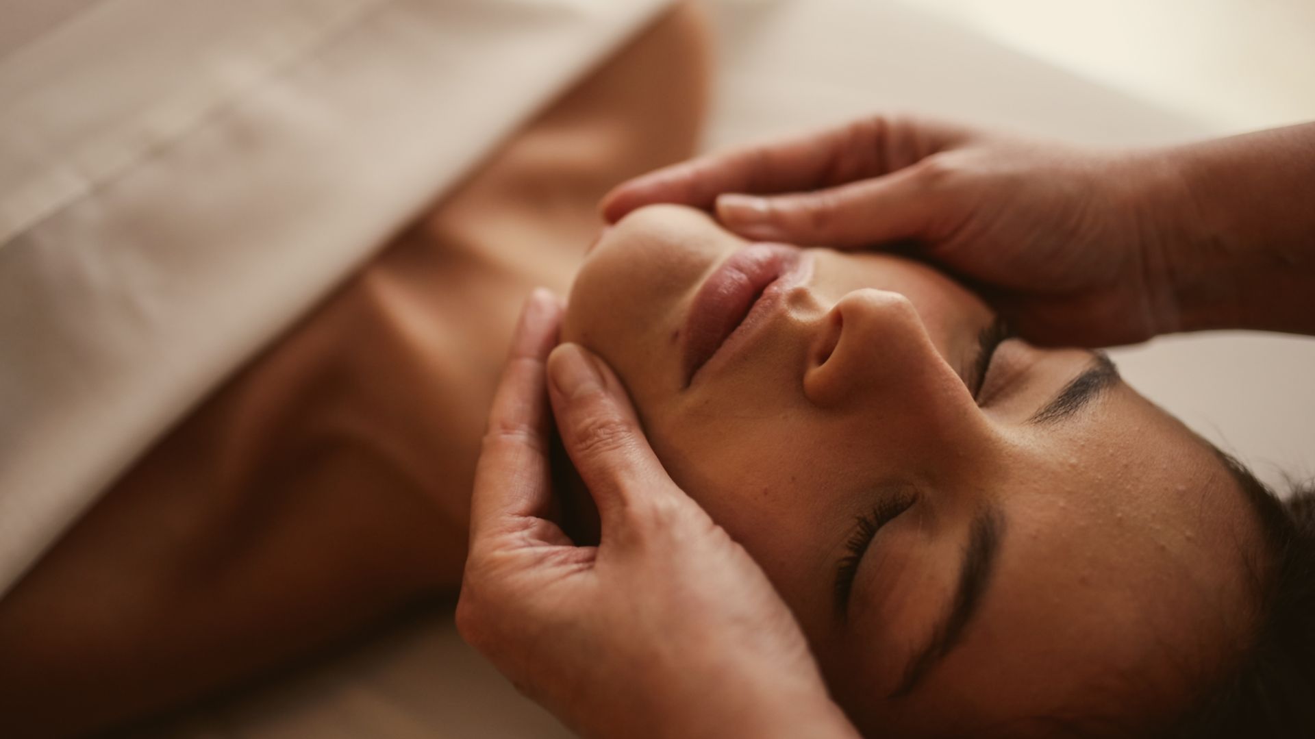 Una mujer recibe un masaje facial en un spa.