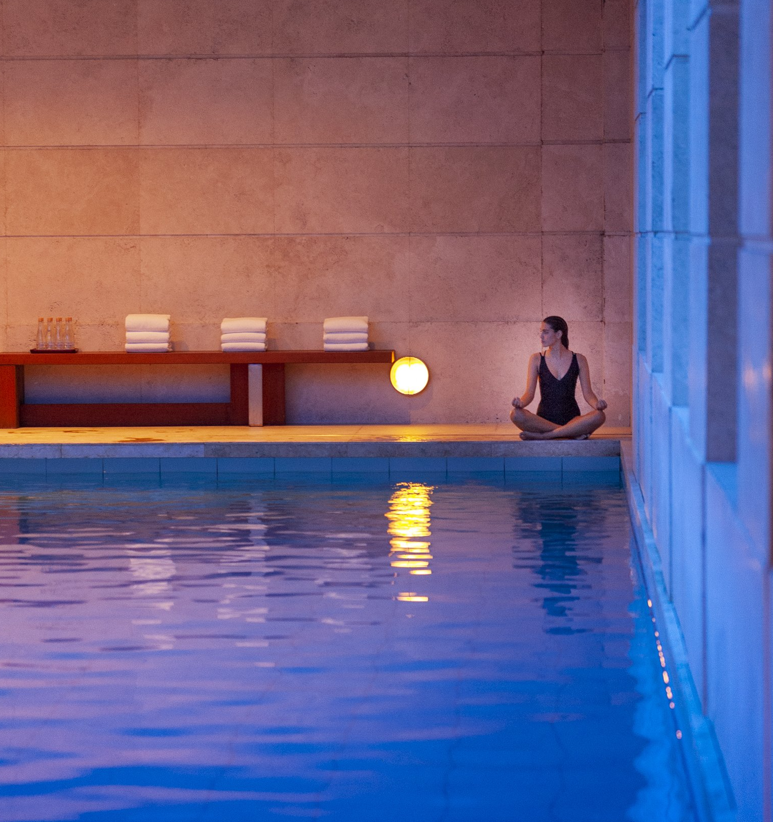 Una mujer sentada al borde de una piscina