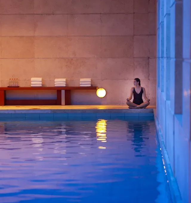 Una mujer sentada en posición de loto al borde de una piscina