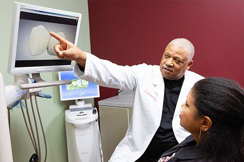 Dr. Davis is pointing at a computer screen while talking to a patient.