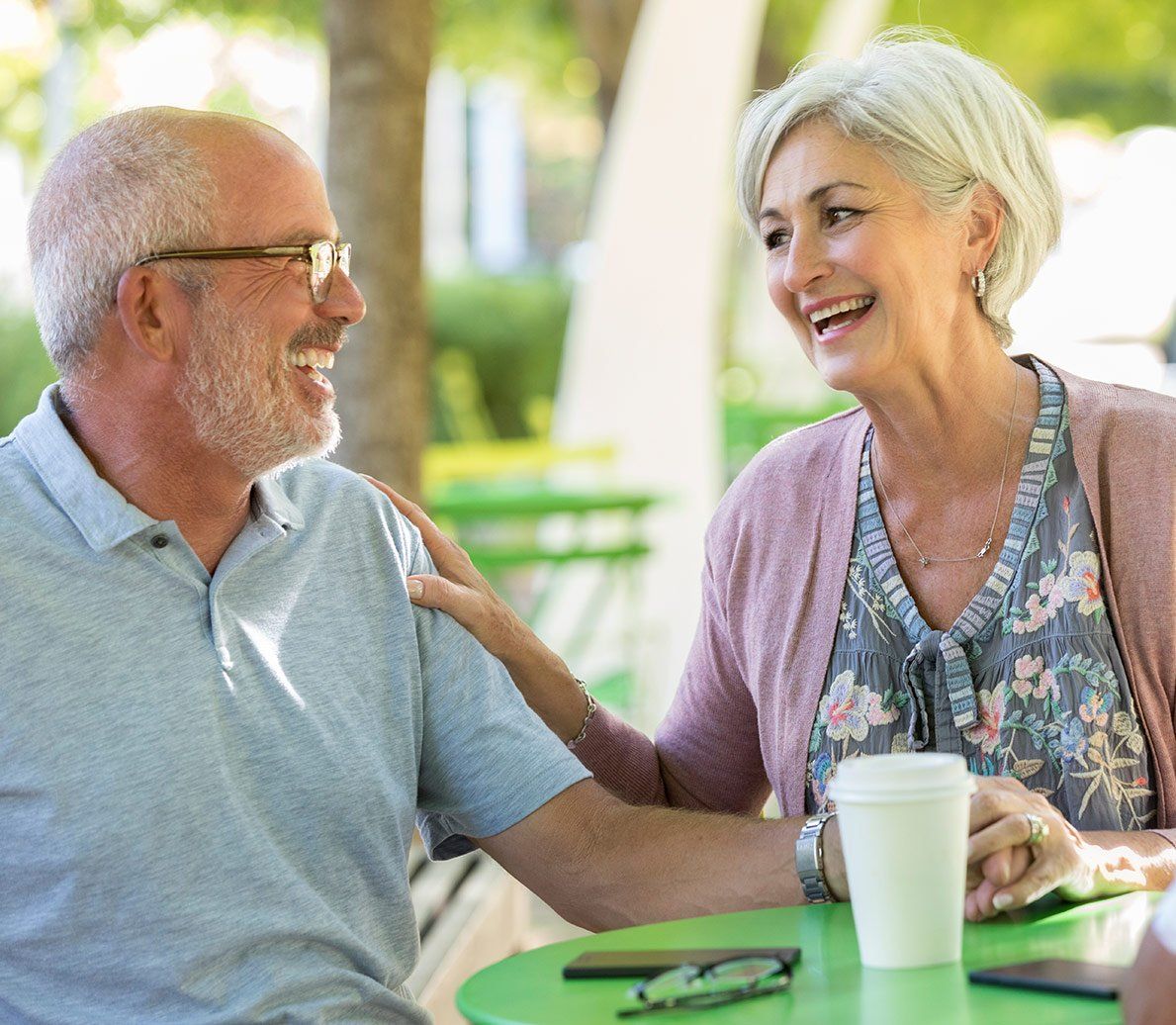 A man and a woman are sitting at a table talking to each other.