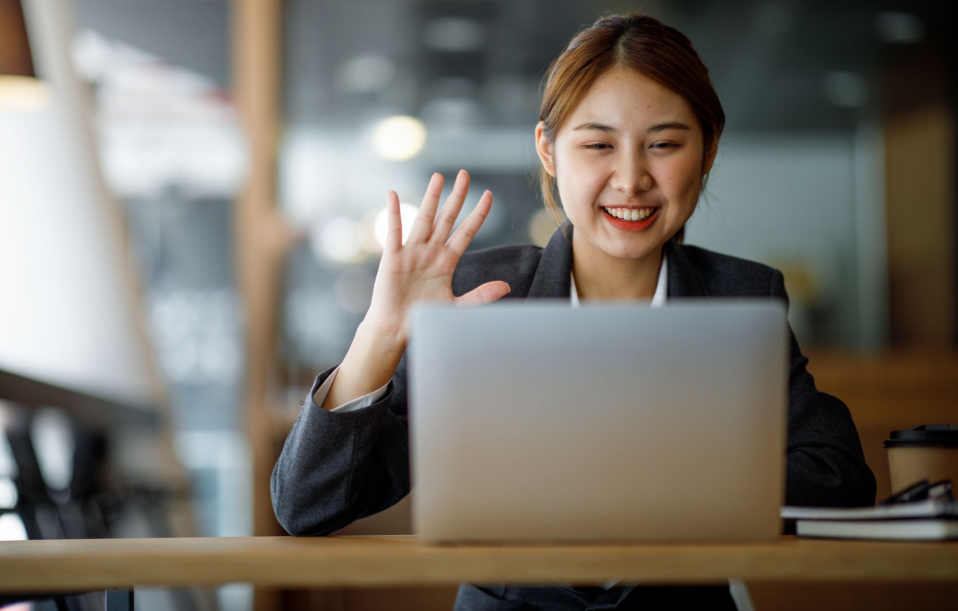 Virtual Assistant waving and using a laptop 