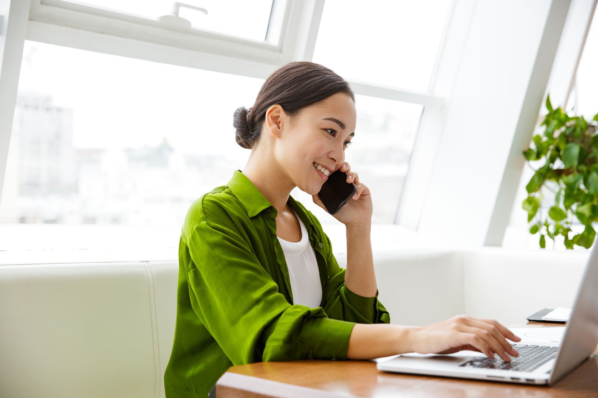 Woman in green using a computer and phone