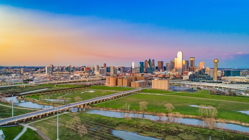 An aerial view of a city skyline at sunset with a river in the foreground. An aerial view of a city skyline at sunset with a river in the foreground.