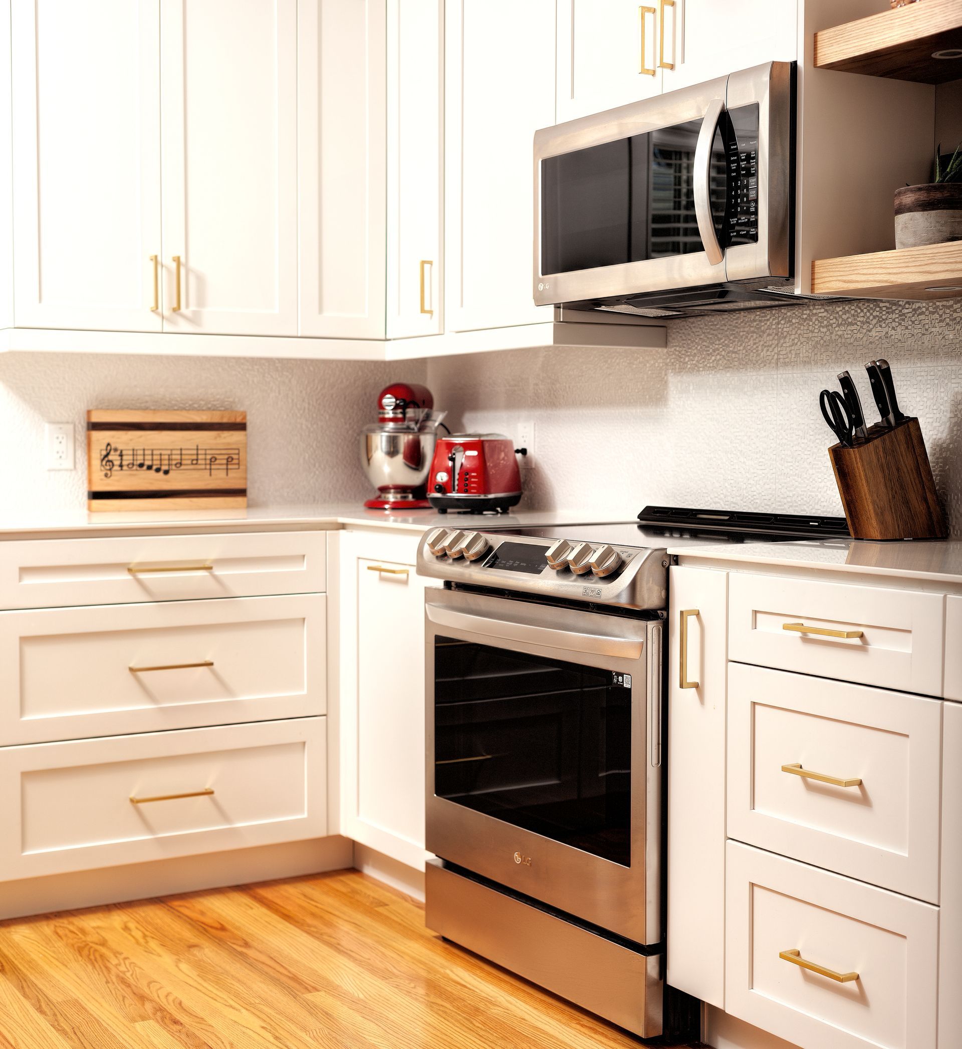 White kitchen with stainless steel appliances and light wood floors.