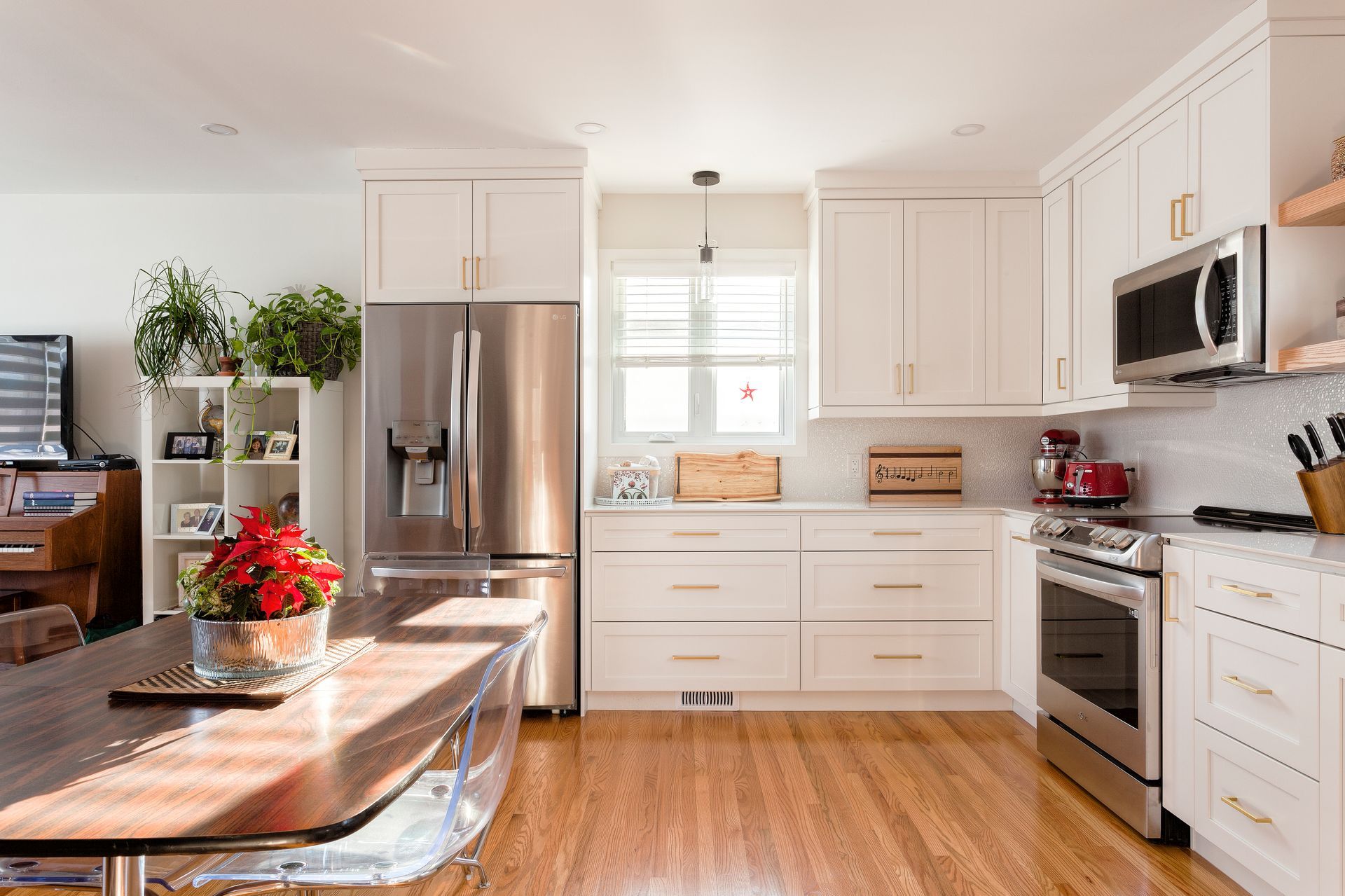 Bright kitchen with white cabinets, stainless steel appliances, and a wooden table.