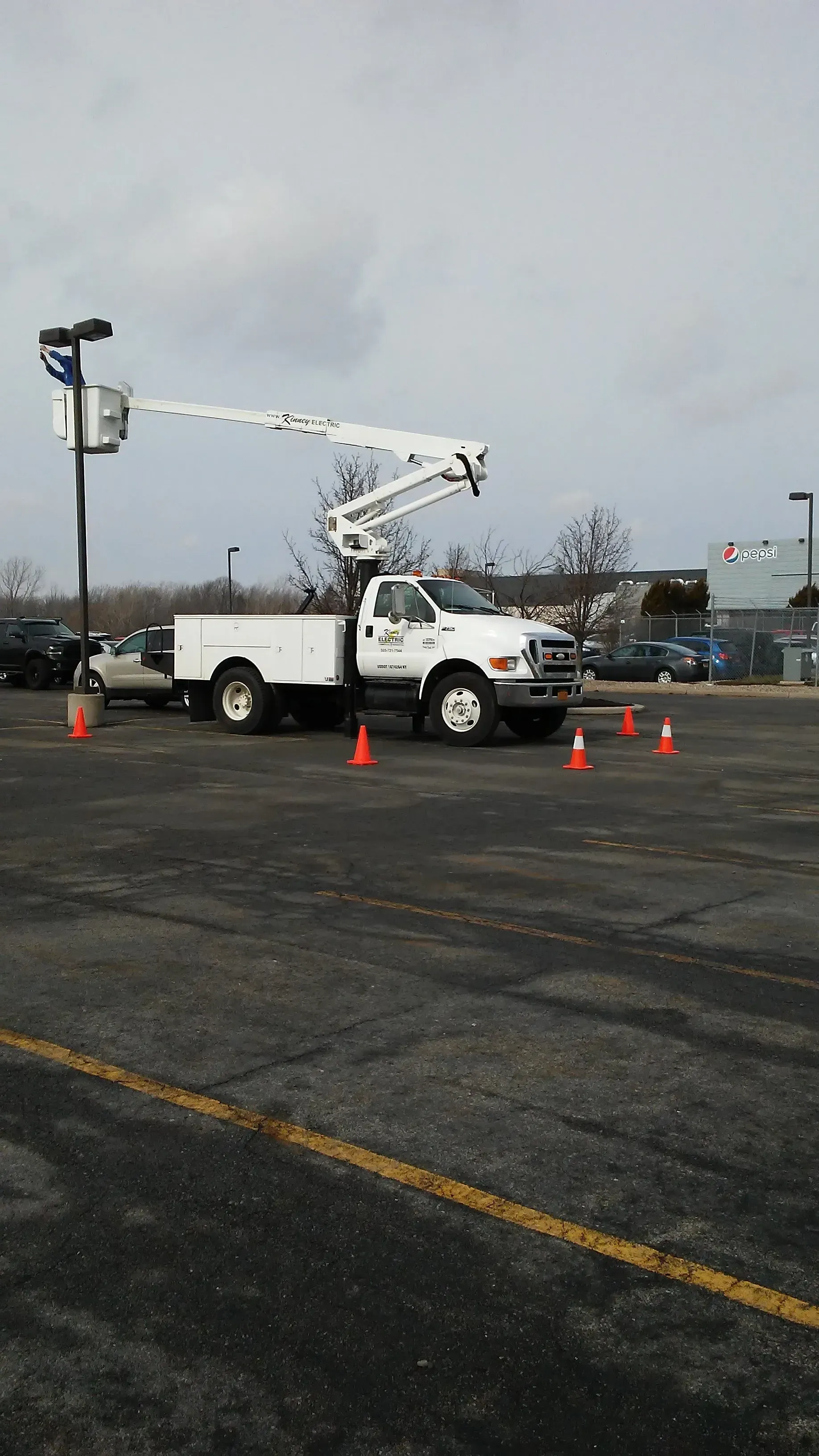 A white truck with a crane on top of it is parked in a parking lot.
