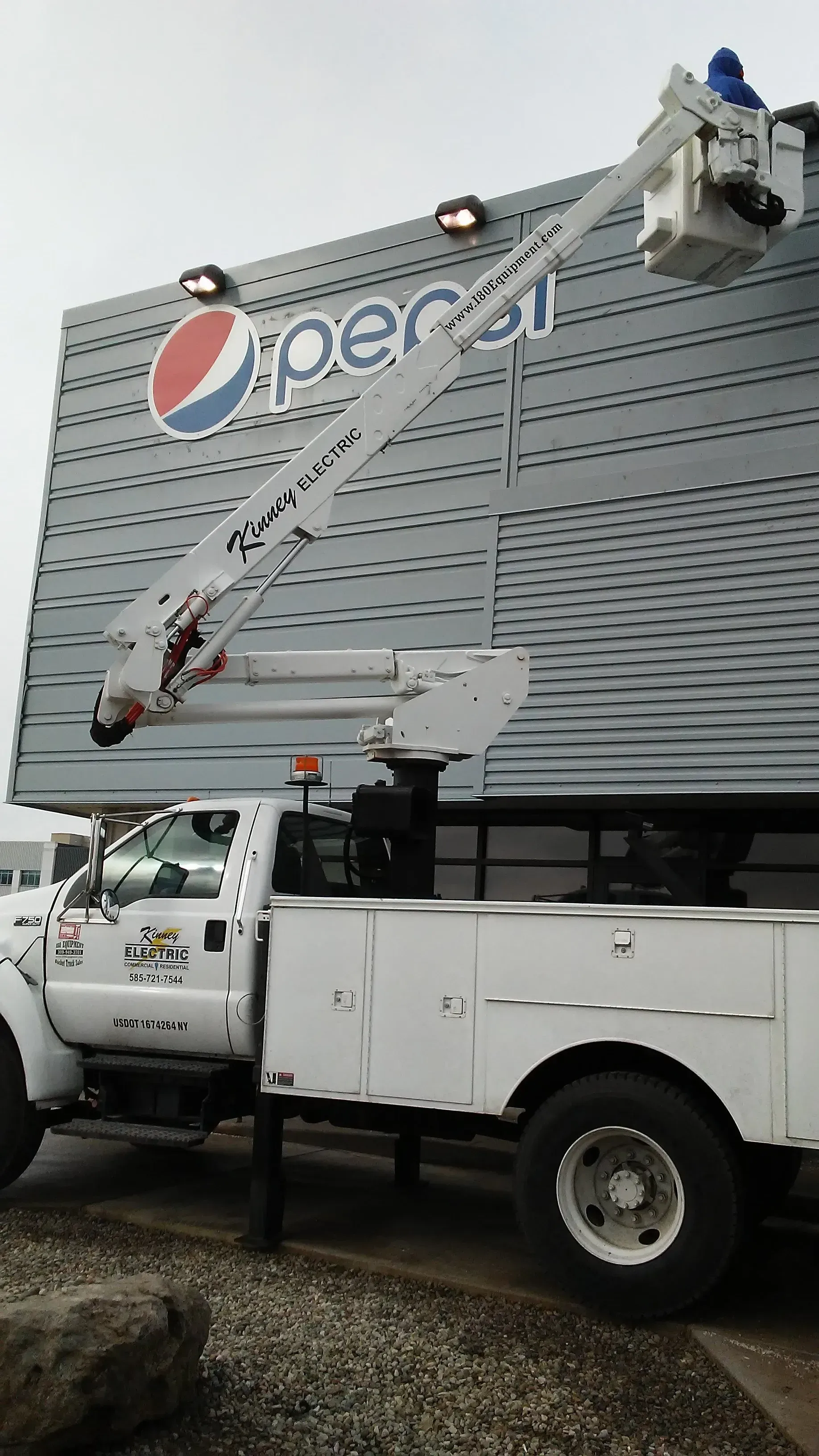 A white truck is parked in front of a large pepsi sign.
