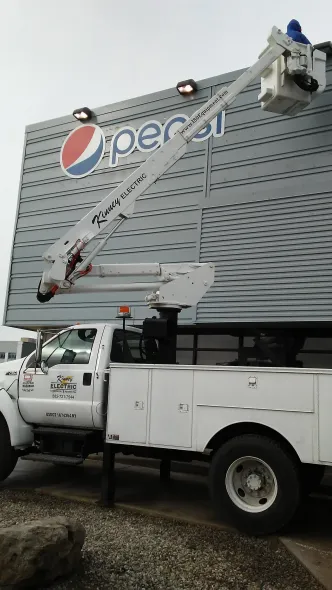 A white truck is parked in front of a large pepsi sign.