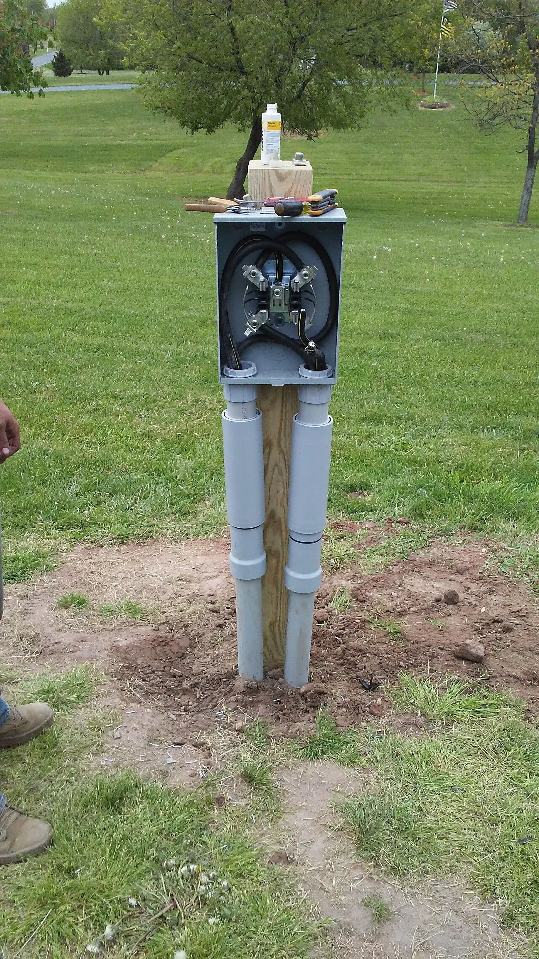 A man is standing next to a mailbox in the middle of a grassy field.