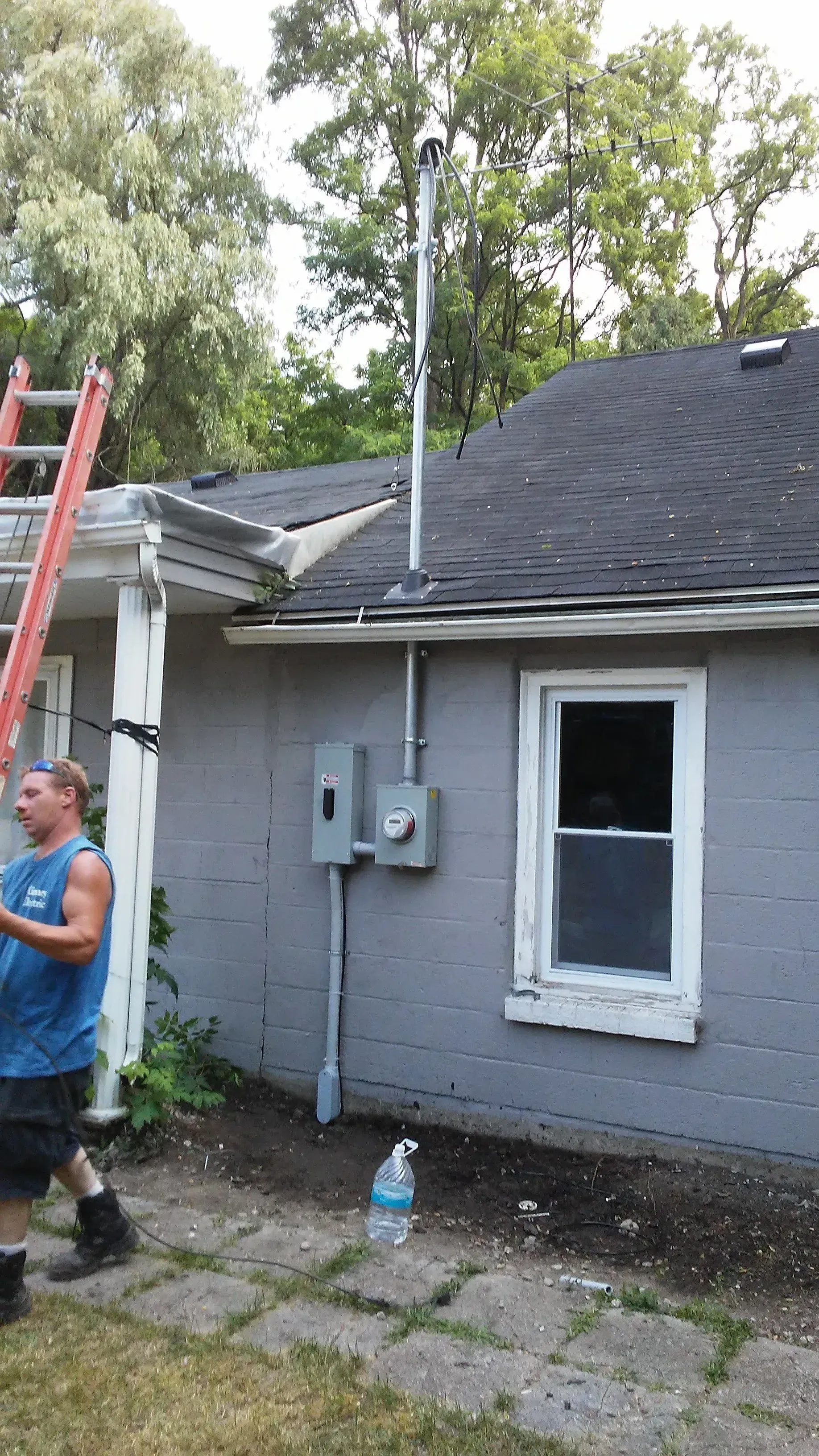 A man is standing in front of a house with a ladder.