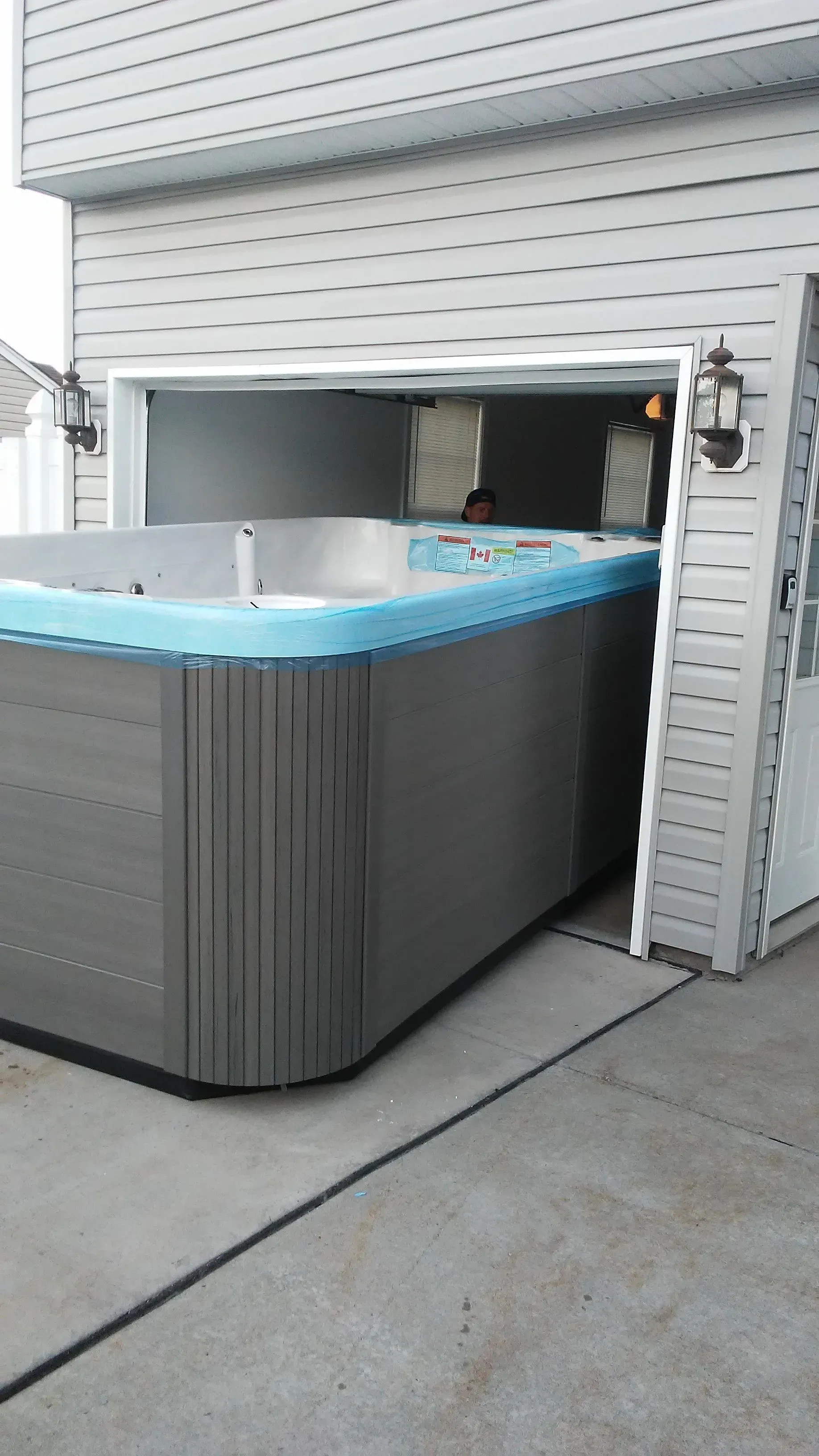 A hot tub is sitting in the driveway of a house.
