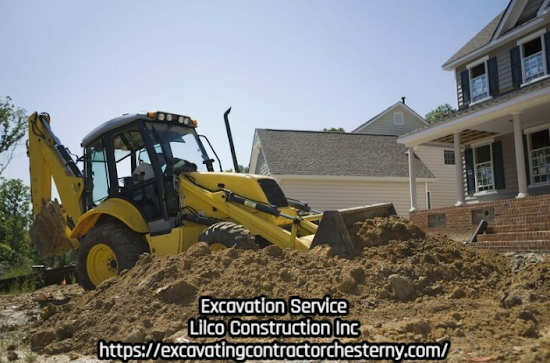 Yellow backhoe excavating earth near a house under a clear sky.  