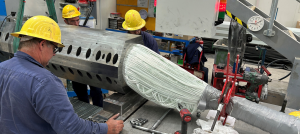 Technicians  in yellow safety helmets working on a machine