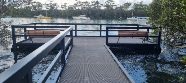 Fibre Reinforced Polymer (FRP) boardwalk over looking a creek where boats are moored
