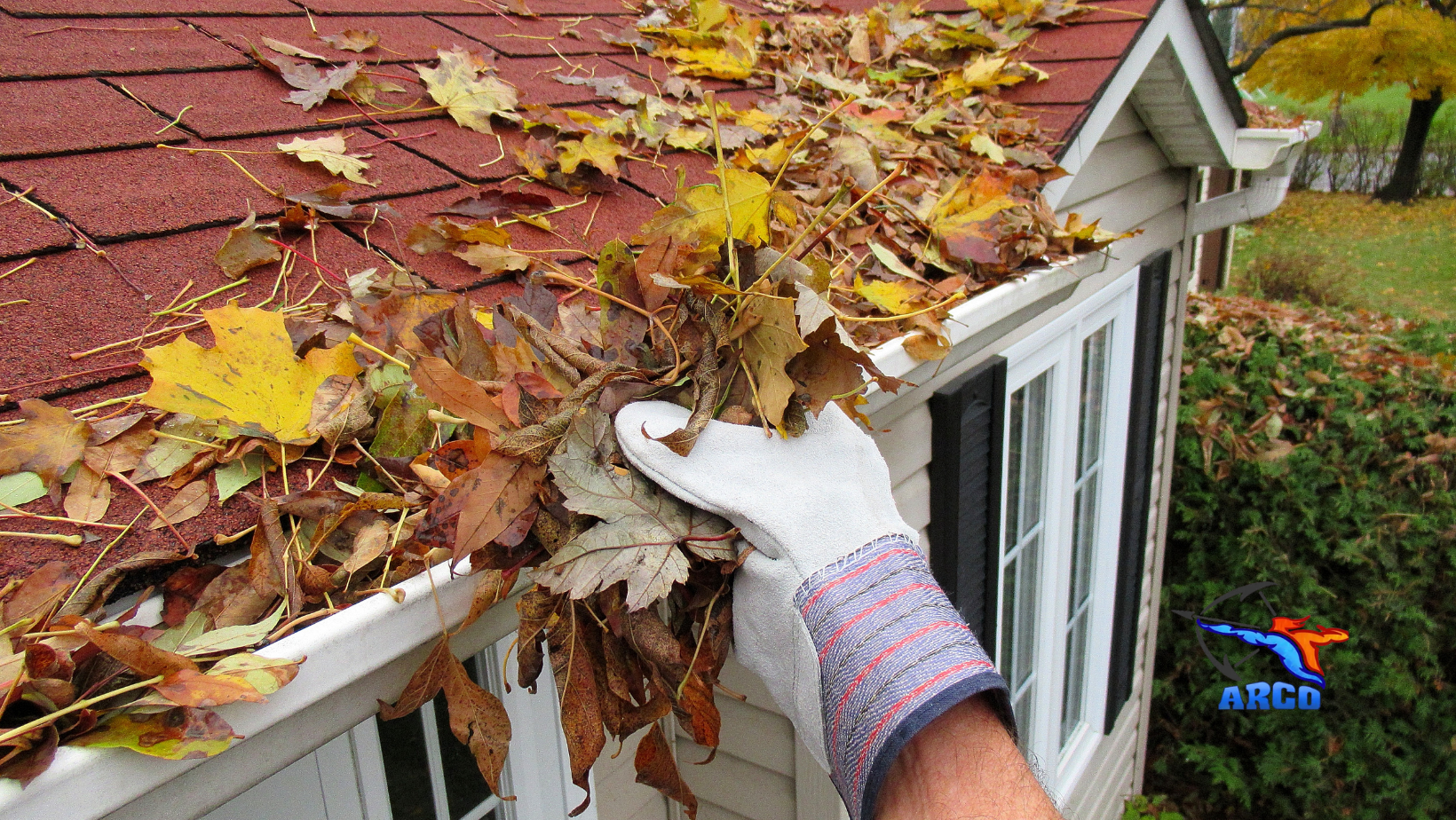 A person is cleaning a gutter of leaves from a mobile home.