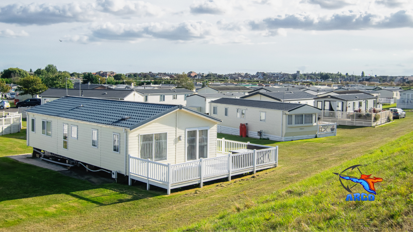 A group of mobile homes are sitting on top of a lush green field.