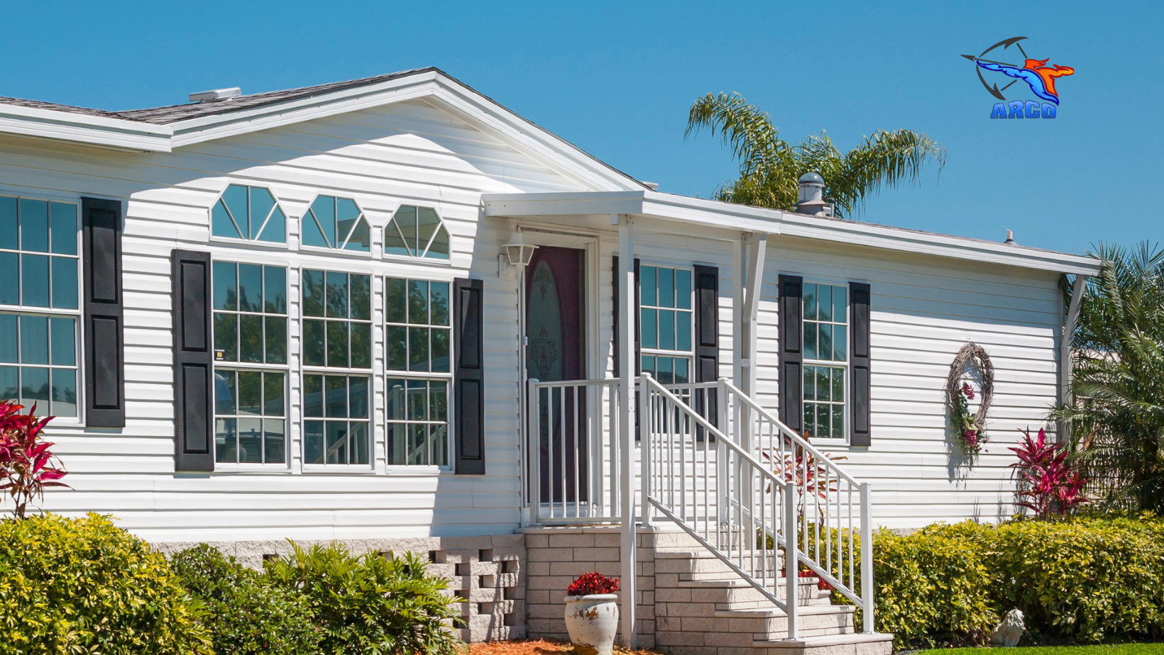 A white mobile home with black shutters and stairs and beautiful door.
