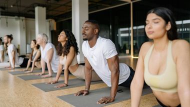 People in a yoga class performing upward-facing dog pose on mats.