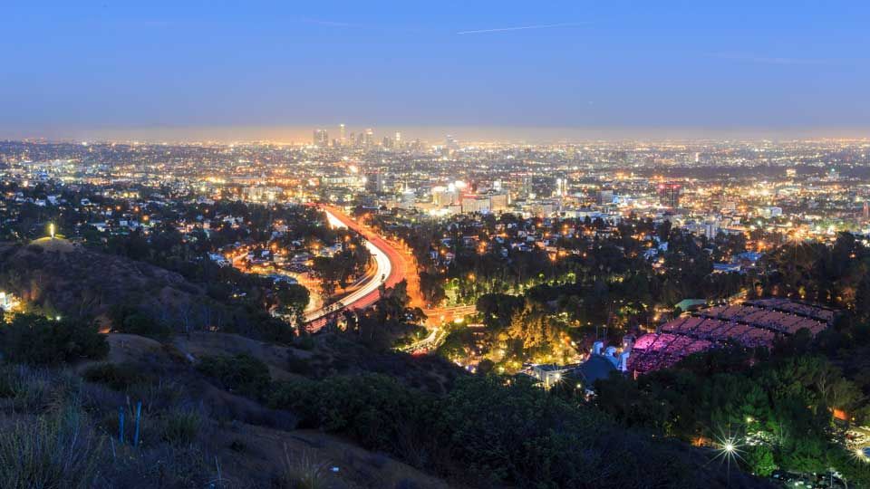 Nighttime cityscape with illuminated roads and buildings, lights against a dark sky.