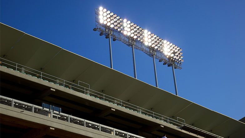 Stadium lights atop a stadium roof against a clear, blue sky.